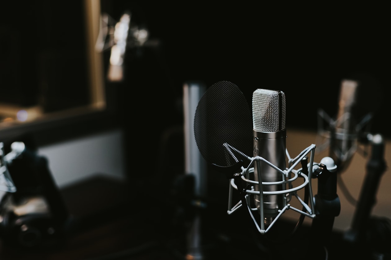 Mand optager podcast med mikrofon og hovedtelefoner i studie